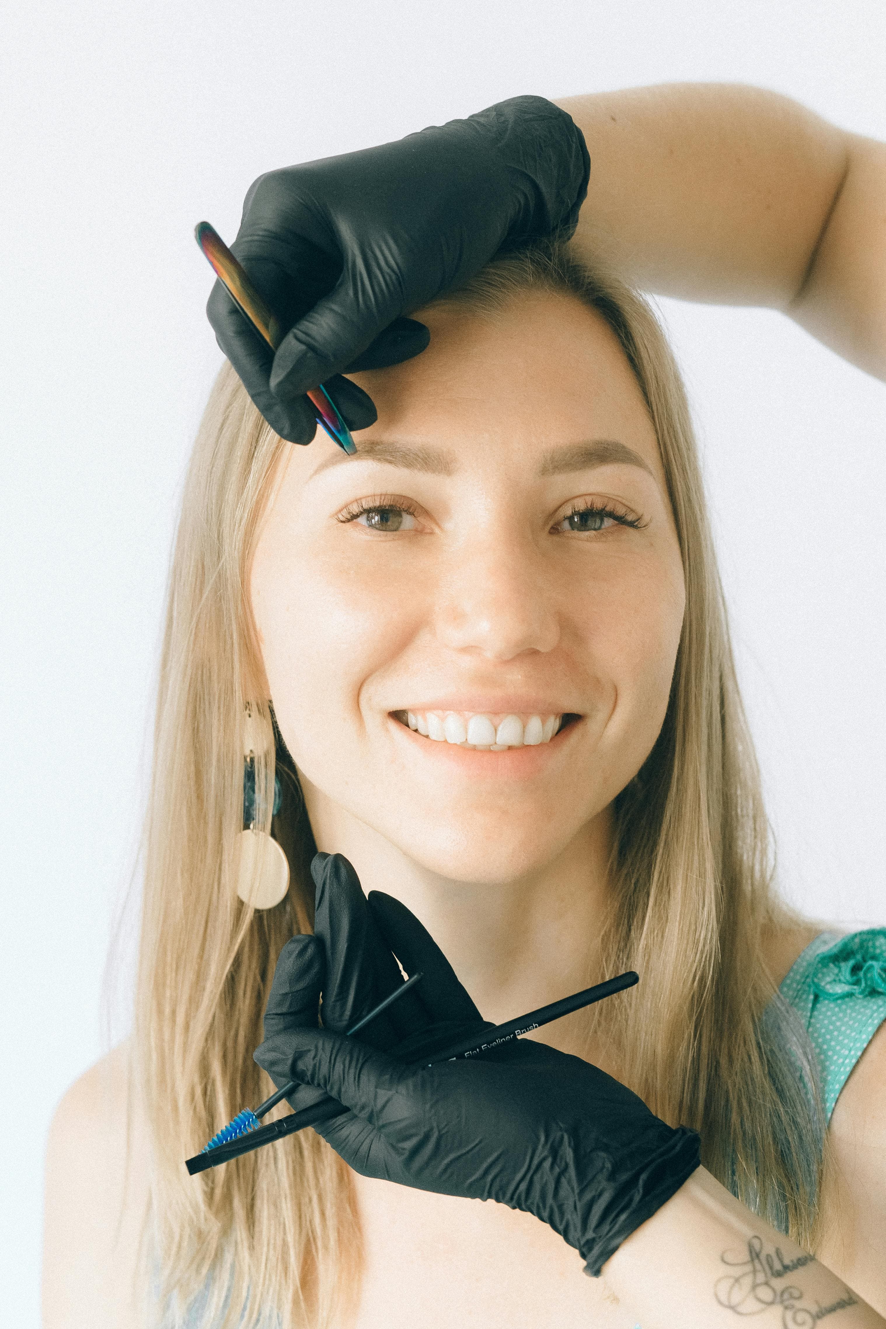 Makeup artist smiling holding brushes in black gloves